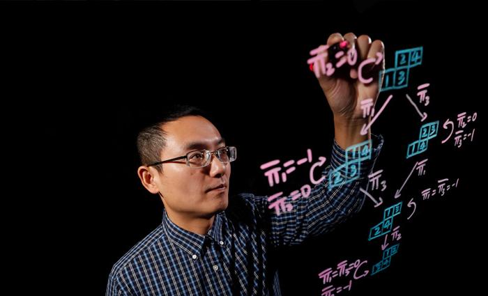 贾强教授在黑板上写方程式